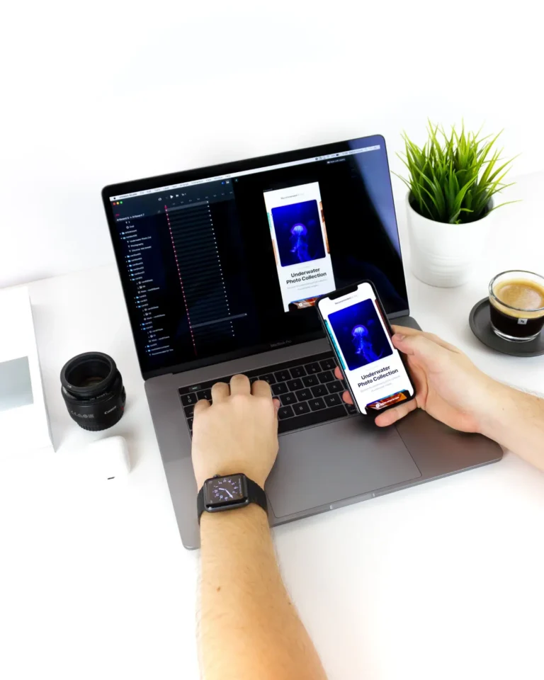 person holding mobile phone in front of a laptop that shares the same screen to signify mobile app development in malaysia.
