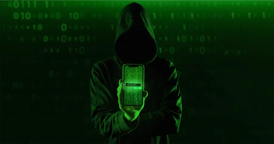 A shrouded figure holding up a phone to warn web developers in Malaysia about cybersecurity threats.